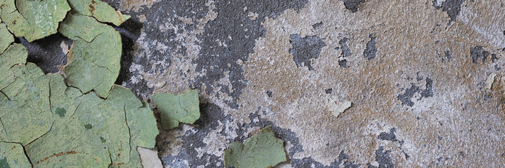 Peeling paint on the wall. Panorama of a concrete wall with old cracked flaking paint. Weathered rough painted surface with patterns of cracks and peeling. Wide panoramic grunge texture for background