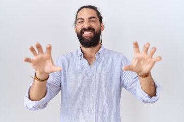 Hispanic man with beard wearing casual shirt smiling funny doing claw gesture as cat, aggressive and sexy expression