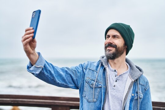 Young bald man smiling confident making selfie by the smartphone at seaside