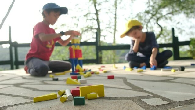 Immerse yourself in the world of childhood imagination with this captivating stock video featuring two children playing outdoors. Watch as they engage in creative play, constructing colorful wooden t
