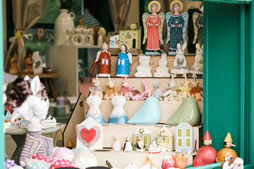 Showcase of a souvenir shop with figurines of toys made of ceramics, fabric and wood. Traditional trade at the city fair, Easter festivities, tourist place.