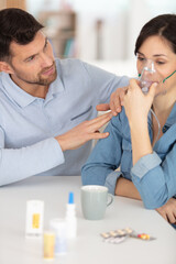 Fototapeta husband watches over wife using oxygen mask at home obraz
