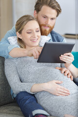 young man and pregnant woman using digital tablet