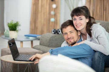 portrait of loving couple with laptop on sofa at home