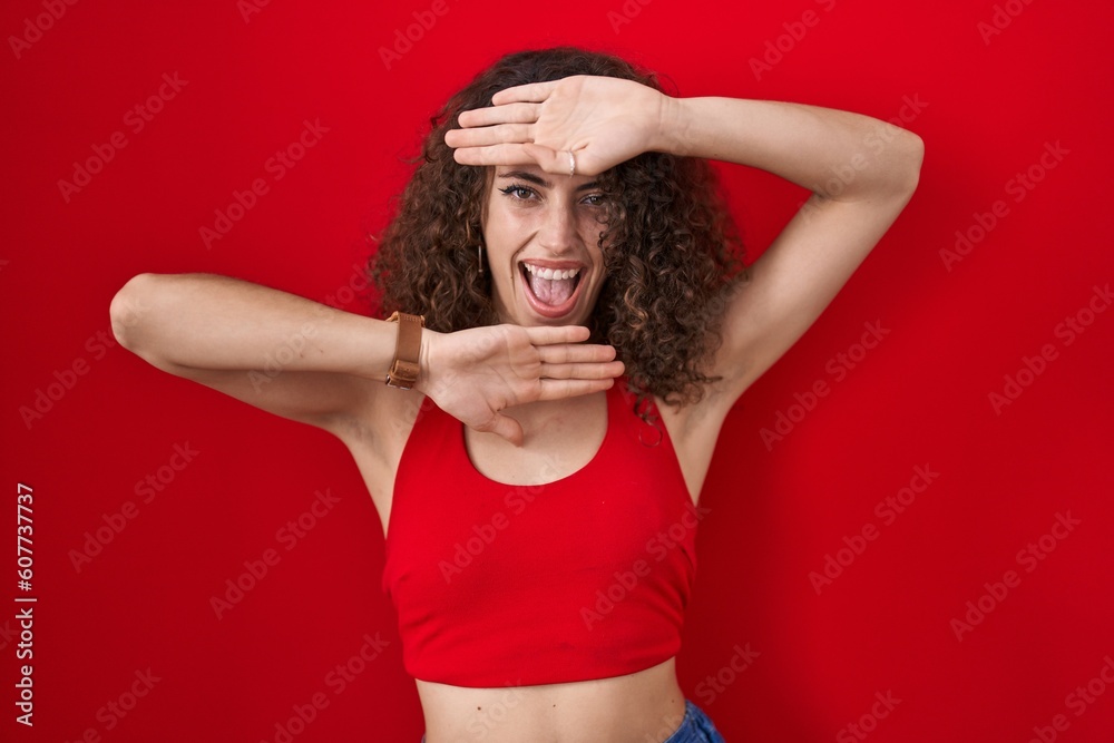 Sticker hispanic woman with curly hair standing over red background smiling cheerful playing peek a boo with