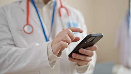 Young hispanic man doctor using smartphone at clinic
