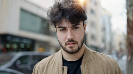 Naklejka premium Young hispanic man standing with serious expression at street