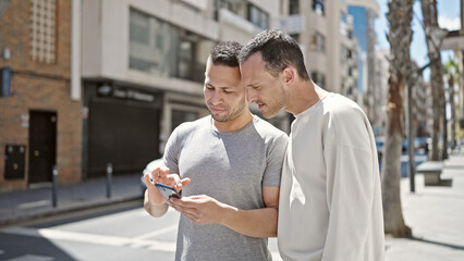 Two men couple looking for destination on smartphone at street