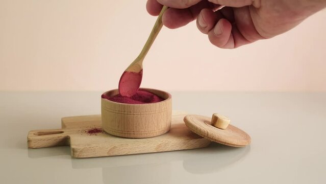 Beetroot powder in wooden bowl. Food additive E 162. Natural red beet pigment. Used in food industry. Dried beetroot powder.