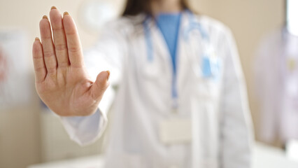 Young caucasian woman doctor doing stop sign with hand at clinic