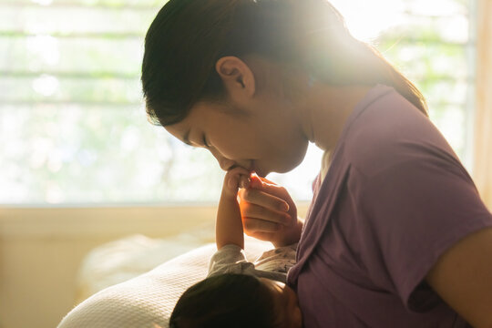 Asian mom is breastfeeding newborn at home.