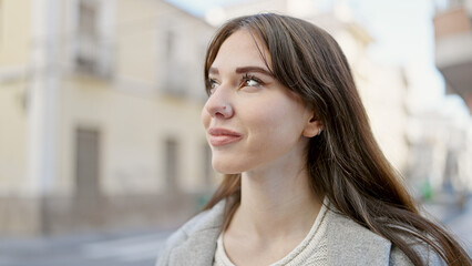 Young hispanic woman standing with serious expression looking to the side at street