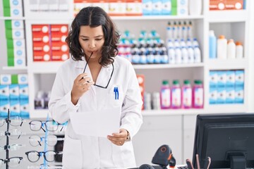 Young woman pharmacist reading paper at pharmacy