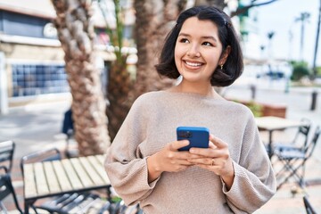 Young woman smiling confident using smartphone at street