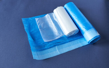 Rolls of blue and white plastic garbage bags on blue background.