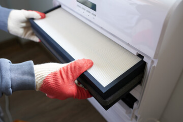 Male hands in gloves cleaning air conditioner indoors, closeup view
