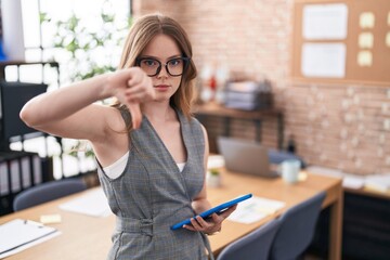 Caucasian woman working at the office wearing glasses looking unhappy and angry showing rejection...