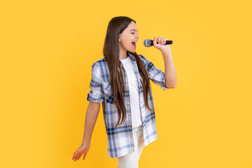 photo of teen girl karaoke singer with microphone. teen girl karaoke singer isolated on yellow