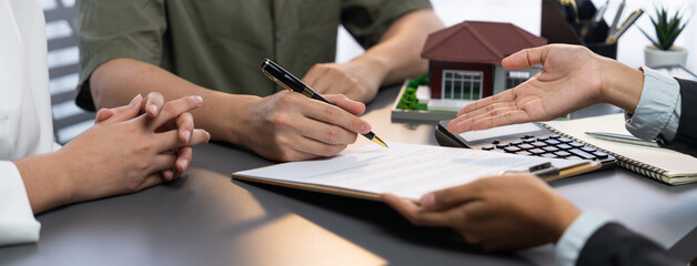 Panorama view of married couple signing house loan contract with real estate agent. Client customer...