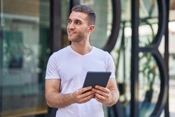 Young caucasian man smiling confident using touchpad at street