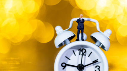 Businessman figurine standing on alarm clock