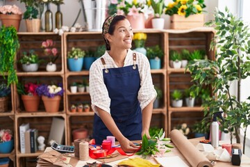 Young beautiful hispanic woman florist make bouquet of flowers at florist