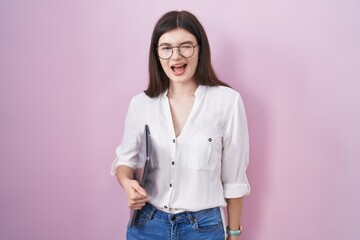 Young caucasian woman holding laptop winking looking at the camera with sexy expression, cheerful...