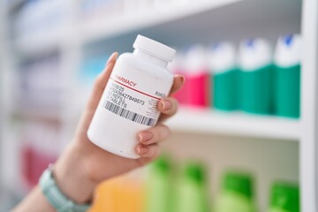 Young caucasian woman holding pills bottle at pharmacy