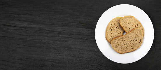 Brown Bread Slices on Black Plate Background