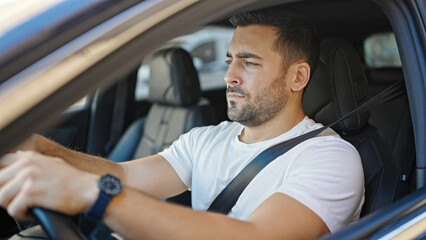 Young hispanic man driving car at street