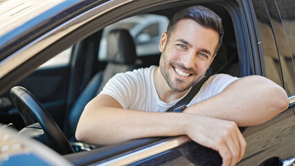 Young hispanic man smiling confident sitting on car at street