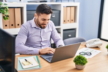 Fototapeta premium Young hispanic man business worker using laptop working at office