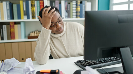 Fototapeta premium African american woman student using computer stressed at library university