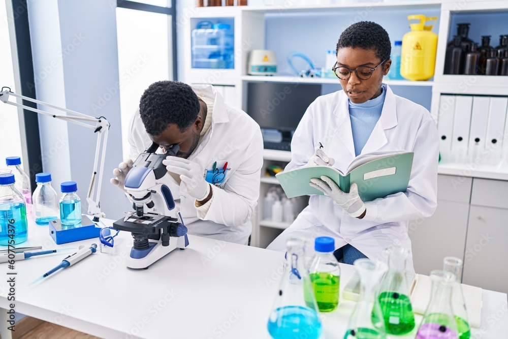 Canvas Prints Man and woman scientists using microscope writing on notebook at laboratory