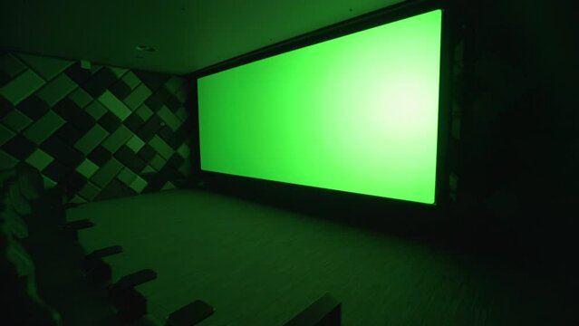 Modern cinema, view of the big green screen in the cinema room, chromakey template in empty cinema hall.