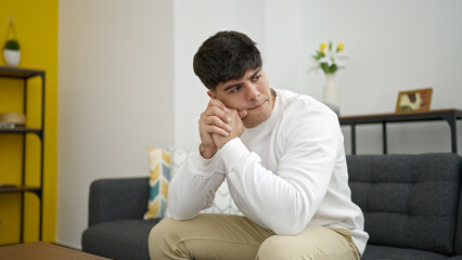Fototapeta premium Young hispanic man stressed sitting on sofa at home