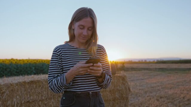 Beautiful and natural looking adult woman use smartphone at sunset. Pretty woman use phone in soft sunset light