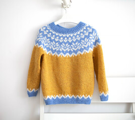 Icelandic wool knitted lopapeysa sweater, yellow blue white pullover with large colorful yoke in traditional Nordic knitting pattern