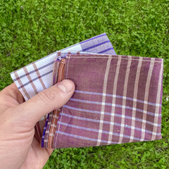 Vintage men's handkerchief in hand on grass background.
