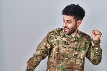 Arab man wearing camouflage army uniform dancing happy and cheerful, smiling moving casual and confident listening to music