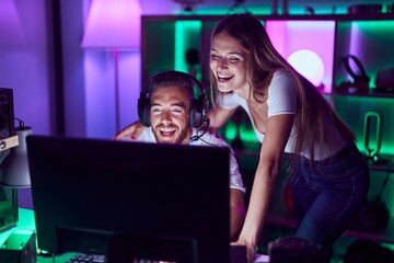 Young couple playing video games smiling and laughing hard out loud because funny crazy joke.