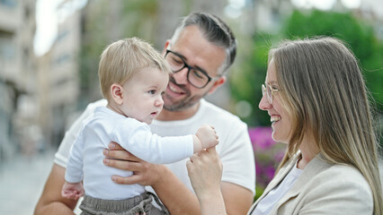 Family of mother, father and baby smiling together at street