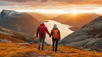 Fototapeta premium Back view of couple holding hands and walking on mountain top at sunset. Generative AI.