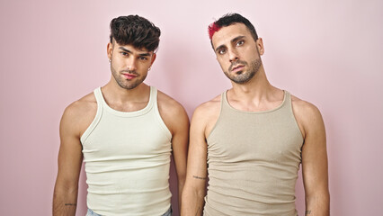 Two men couple standing together with relaxed expression over isolated pink background