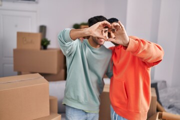 Two man couple doing heart gesture with hands at new home