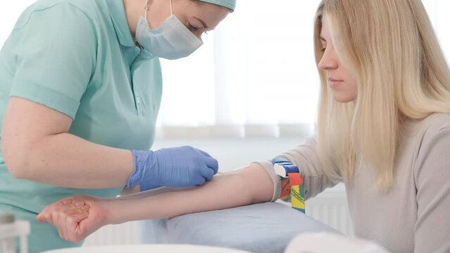 A doctor in a hospital gently draws blood from a girl for diagnostic tests.