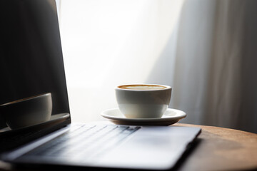 Start your working day with hot latte coffee cup background, laptop and mobile phone at work.