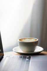 Start your working day with hot latte coffee cup background, laptop and mobile phone at work.