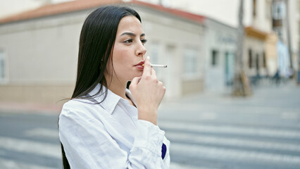 Fototapeta premium Young beautiful hispanic woman smoking at street