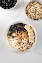Homemade granola with Greek yogurt, almonds, blueberries and banana in a bowl. 